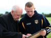 Fr McCorry, who was a member of the Antrim team who won the county's last Ulster Senior Football title back in 1951, shows a photo of the team to current captain Paddy Cunningham at Monday evening's press night in Creggan. 